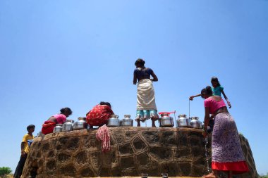 Maharashtra, Hindistan / 6 Mayıs 2016: Kadınlar, Dhakne köyü, Shahapur Taluka, Thane İlçesi 'ndeki neredeyse kuru bir kuyudan su getiriyor