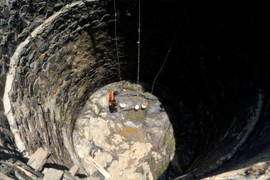 Maharashtra, Hindistan / 6 Mayıs 2016: Genç bir çocuk, Dhakne Köyü, Shahapur Taluka, Thane İlçesi 'ndeki neredeyse kuru bir kuyudan su almak için derin bir kuyuya iniyor