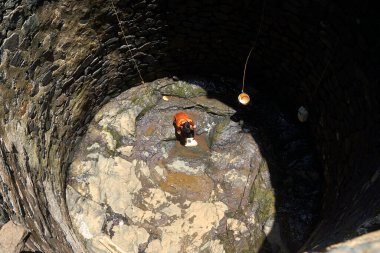 Maharashtra, Hindistan / 6 Mayıs 2016: Genç bir çocuk, Dhakne Köyü, Shahapur Taluka, Thane İlçesi 'ndeki neredeyse kuru bir kuyudan su almak için derin bir kuyuya iniyor