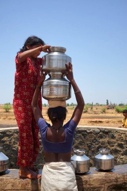 Maharashtra, Hindistan / 6 Mayıs 2016: Kadınlar, Dhakne köyü, Shahapur Taluka, Thane İlçesi 'ndeki neredeyse kuru bir kuyudan su getiriyor