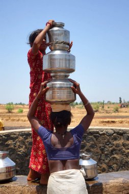 Maharashtra, Hindistan / 6 Mayıs 2016: Kadınlar, Dhakne köyü, Shahapur Taluka, Thane İlçesi 'ndeki neredeyse kuru bir kuyudan su getiriyor
