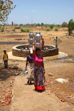 Maharashtra, Hindistan / 6 Mayıs 2016: Kadınlar, Dhakne köyü, Shahapur Taluka, Thane İlçesi 'ndeki neredeyse kuru bir kuyudan su getiriyor