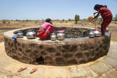 Maharashtra, Hindistan / 6 Mayıs 2016: Kadınlar, Dhakne köyü, Shahapur Taluka, Thane İlçesi 'ndeki neredeyse kuru bir kuyudan su getiriyor