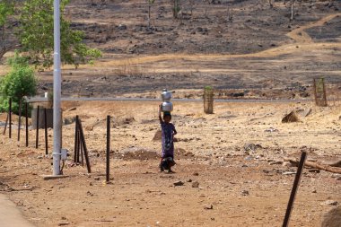 Maharashtra, Hindistan / 6 Mayıs 2016: Genç bir kız, Dhakne köyü, Shahapur Taluka, Thane County 'deki neredeyse kuru bir kuyudan su getirmek için paslanmaz konteynır taşıyor