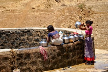 Maharashtra, Hindistan / 6 Mayıs 2016: Kadınlar, Dhakne köyü, Shahapur Taluka, Thane İlçesi 'ndeki neredeyse kuru bir kuyudan su getiriyor