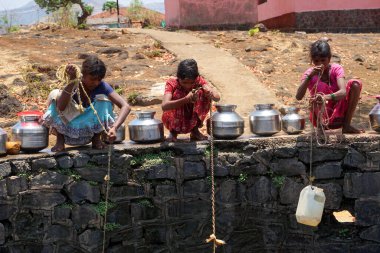 Maharashtra, Hindistan / 6 Mayıs 2016: Çocuklar, Dhakne köyü, Shahapur Taluka, Thane İlçesi 'ndeki neredeyse kuru bir kuyudan su getiriyor