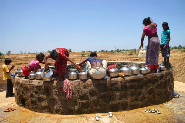 Maharashtra, Hindistan / 6 Mayıs 2016: Kadınlar, Dhakne köyü, Shahapur Taluka, Thane İlçesi 'ndeki neredeyse kuru bir kuyudan su getiriyor