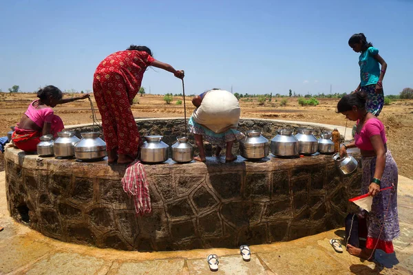 Maharashtra, Hindistan / 6 Mayıs 2016: Kadınlar, Dhakne köyü, Shahapur Taluka, Thane İlçesi 'ndeki neredeyse kuru bir kuyudan su getiriyor