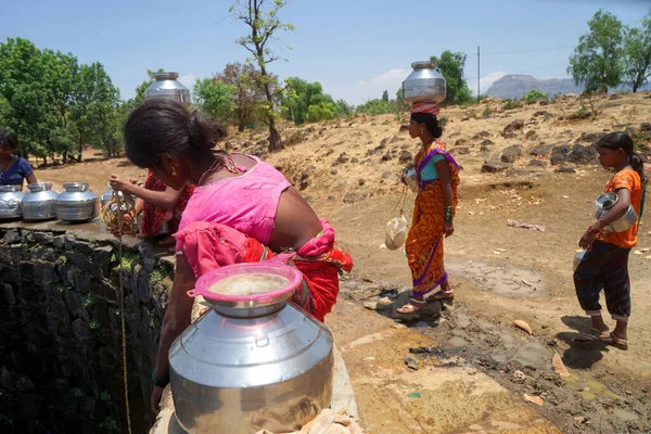 Maharashtra, Hindistan / 6 Mayıs 2016: Kadınlar, Dhakne köyü, Shahapur Taluka, Thane İlçesi 'ndeki neredeyse kuru bir kuyudan su getiriyor