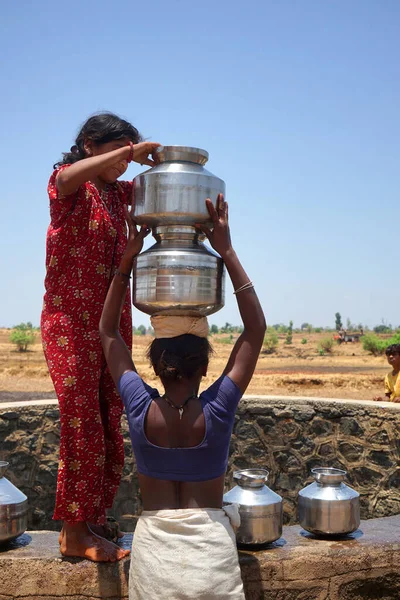 Maharashtra, Hindistan / 6 Mayıs 2016: Kadınlar, Dhakne köyü, Shahapur Taluka, Thane İlçesi 'ndeki neredeyse kuru bir kuyudan su getiriyor