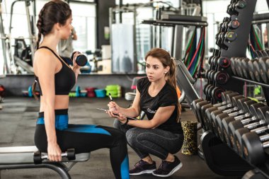 Güzel bir kadının spor salonunda egzersiz profesyonel kişisel antrenör izler