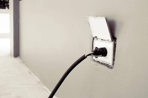 The plug is plugged into a wall outlet at outside of house