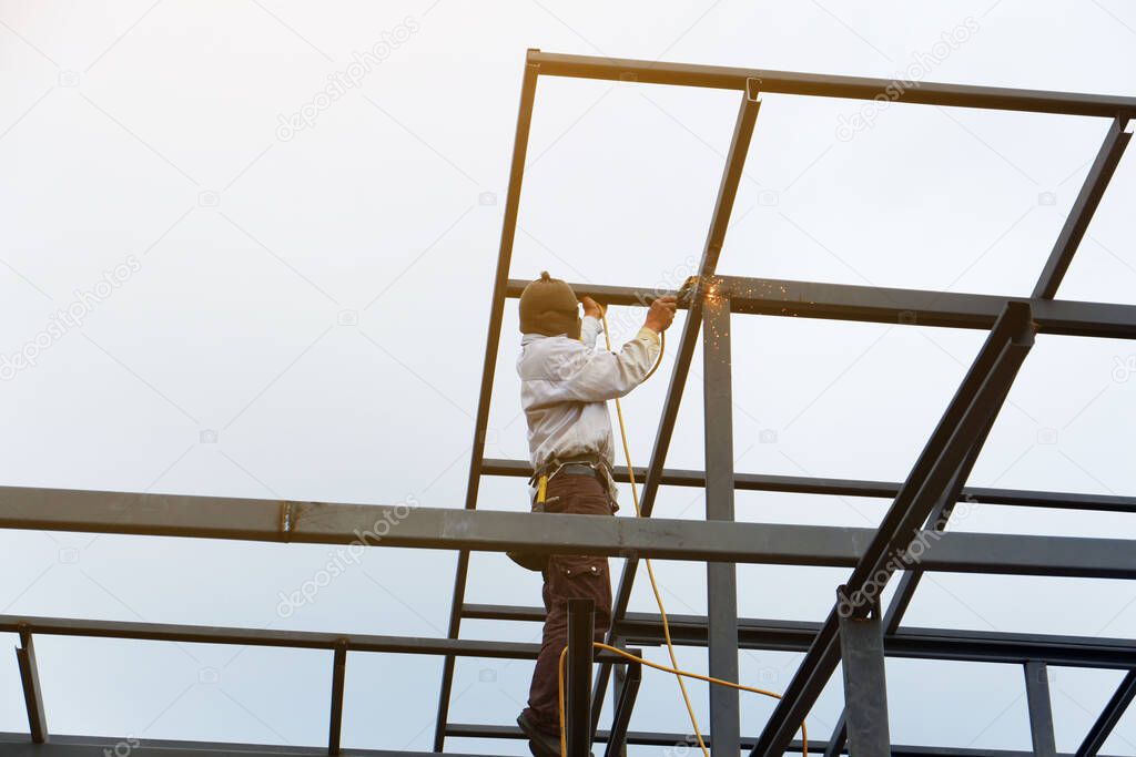 Welders are welding steel roof frame of home