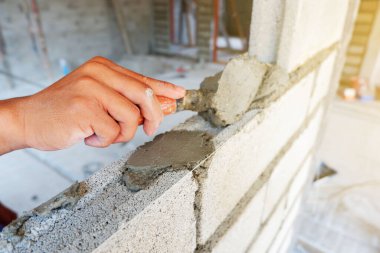 Duvarcının eli beton bloklu duvar inşaatında çalışıyor.