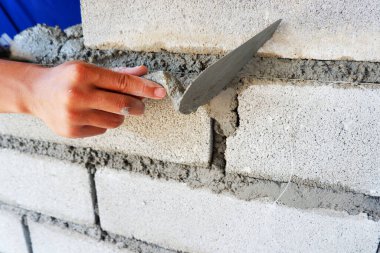 Duvarcının eli beton bloklu duvar inşaatında çalışıyor.