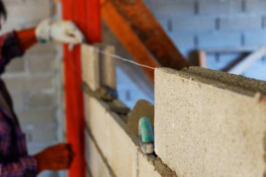 Duvarcı, beton tuğla duvar inşaatından önce katı bulmak için halatı çeker.
