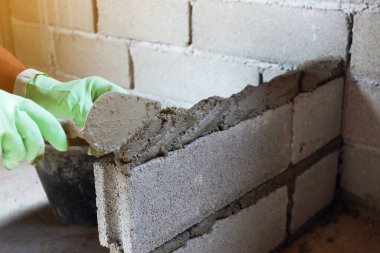 Adam tuğla ustası beton blok duvarlarını mala kullanarak inşa ediyor..