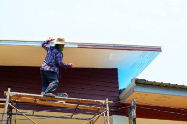 Ressam, yazın sıcağında çatıyı boyuyor.