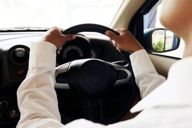 Adam arabanın direksiyonunu kontrol etmek için elinde tutuyor. Arkaya bakan yolcuların fotoğrafını çekiyor.