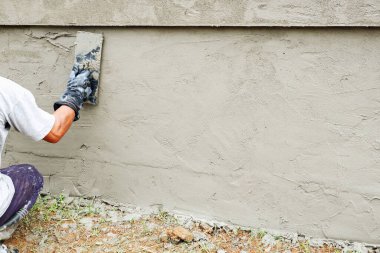 Duvarcı tuğla blok çitinde çimento kaplıyor.