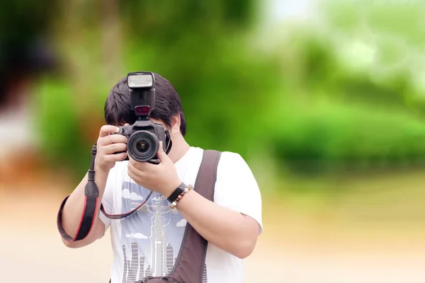 写真家がカメラを手に取り ぼかしを背景に写真を撮る — ストック写真