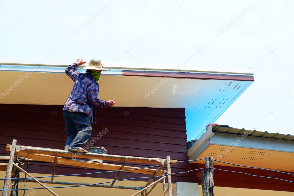 painter is painting the roof In the hot weather of summer