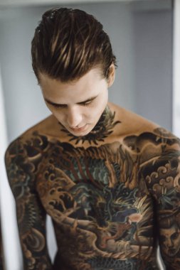 bir ayna, onun elinde bir tıraş jilet önünde genç bir yakışıklı dövmeli adam sabah tıraş.