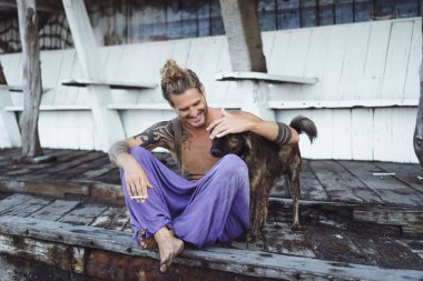 Uzun sarı saçlı ve köpekle oynamayı dövmeler yakışıklı yetişkin adam