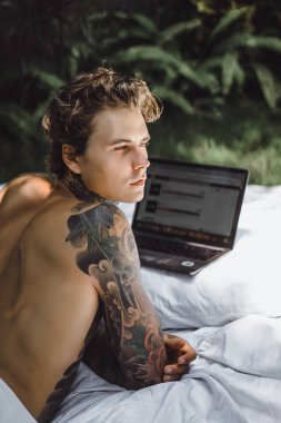 bir dizüstü bilgisayarda çalışan, posta kontrol, bir film seyrederken yatakta bir adam müzik