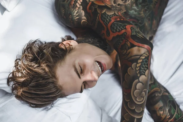 Csinos Fiatal Tetovált Férfi Pihentető Fehér Ágy — Stock Fotó