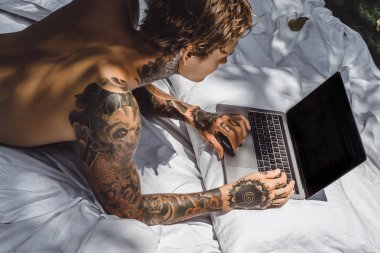 bir dizüstü bilgisayarda çalışan, posta kontrol, bir film seyrederken yatakta bir adam müzik