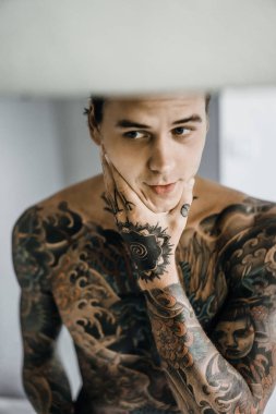 bir ayna, onun elinde bir tıraş jilet önünde genç bir yakışıklı dövmeli adam sabah tıraş.