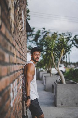 Bir havuzda pateni bir şık genç adam bir skatepark, bir kaykay üzerinde beyaz bir T-shirt ve şapka paten.