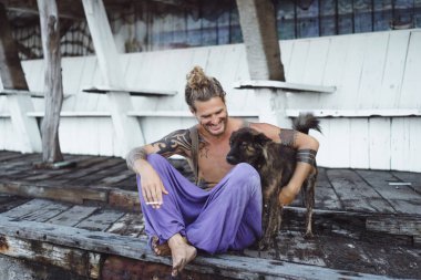 Uzun sarı saçlı ve köpekle oynamayı dövmeler yakışıklı yetişkin adam