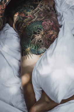 yakışıklı, Genç bir dövmeli adam sabah yatakta yastık fırlatır. Bahçe yatağında