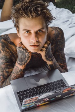 bir dizüstü bilgisayarda çalışan, posta kontrol, bir film seyrederken yatakta bir adam müzik
