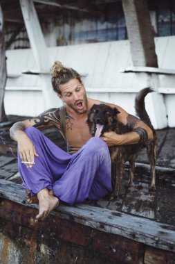 Uzun sarı saçlı ve köpekle oynamayı dövmeler yakışıklı yetişkin adam