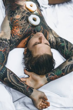 Genç yakışıklı adam açık havada bahçede açık havada yatakta kahvaltı dövme