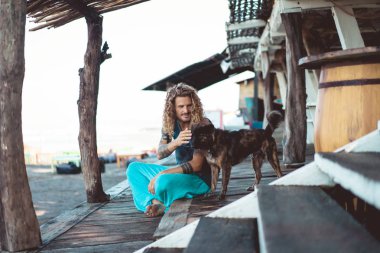 Uzun sarı saçlı ve köpekle oynamayı dövmeler yakışıklı yetişkin adam