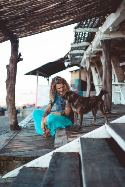 Uzun sarı saçlı ve köpekle oynamayı dövmeler yakışıklı yetişkin adam