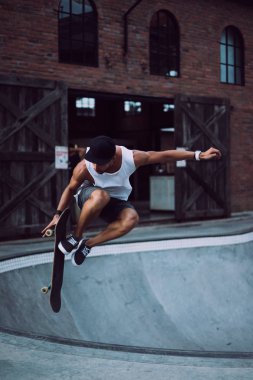 Bir havuzda pateni bir şık genç adam bir skatepark, bir kaykay üzerinde beyaz bir T-shirt ve şapka paten.