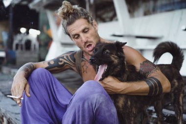 Uzun sarı saçlı ve köpekle oynamayı dövmeler yakışıklı yetişkin adam