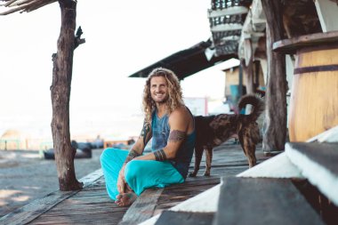 Uzun sarı saçlı ve köpekle oynamayı dövmeler yakışıklı yetişkin adam