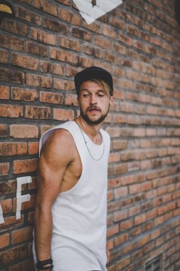 Bir havuzda pateni bir şık genç adam bir skatepark, bir kaykay üzerinde beyaz bir T-shirt ve şapka paten.