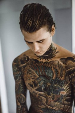 bir ayna, onun elinde bir tıraş jilet önünde genç bir yakışıklı dövmeli adam sabah tıraş.