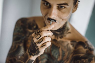 bir ayna, onun elinde bir tıraş jilet önünde genç bir yakışıklı dövmeli adam sabah tıraş.