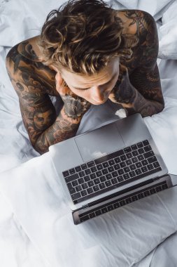 bir dizüstü bilgisayarda çalışan, posta kontrol, bir film seyrederken yatakta bir adam müzik