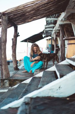 Uzun sarı saçlı ve köpekle oynamayı dövmeler yakışıklı yetişkin adam