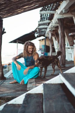 Uzun sarı saçlı ve köpekle oynamayı dövmeler yakışıklı yetişkin adam