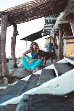 Uzun sarı saçlı ve köpekle oynamayı dövmeler yakışıklı yetişkin adam